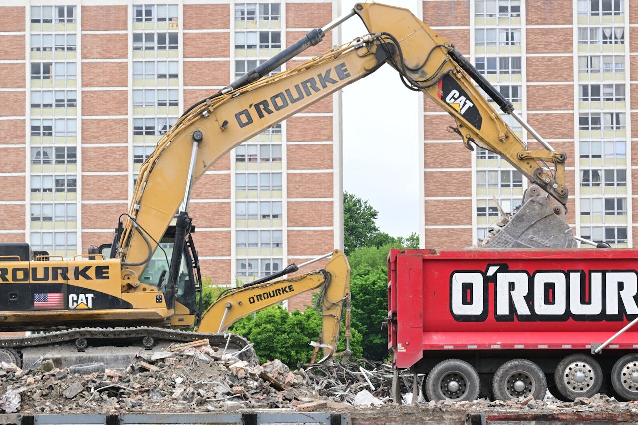 Heavy machinery at a construction site in Covington, KY with debris and building backdrop.
